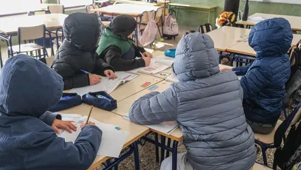 Diferentes alumnos con chaquetones y plumas puestos en las clases.