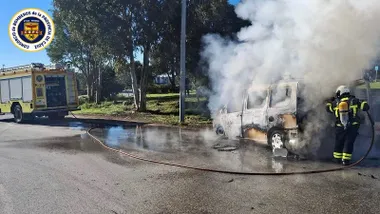 Camión de bombero junto al coche calcinado, sofoca el incendio un bombero.