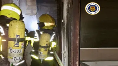 Dos bomberos accediendo al interior de la vivienda incendiada en Chipiona.