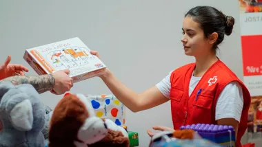 Chica de la Cruz Roja entregando un juguete.