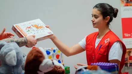 Chica de la Cruz Roja entregando un juguete.
