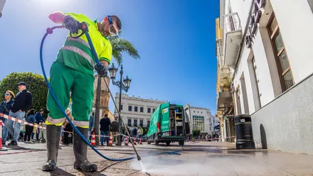 Un operario municipal de limpieza de San Fernando limpia el pavimento con una pistola a presión de agua