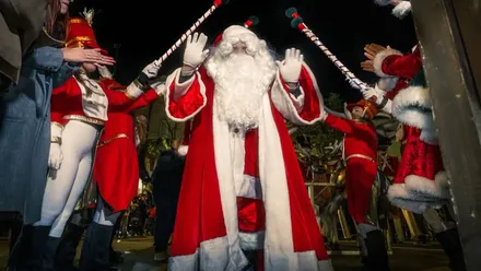 Papa Noel con su traje rojo y blanco saludando a las personas.