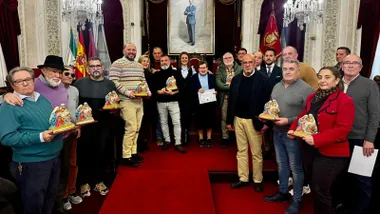 Foto de familia de los premiados y representantes municipales al término del acto de entrega del Concurso de Nacimientos de la Navidad 2025, celebrado en el Salón de Plenos del Ayuntamiento de Cádiz
