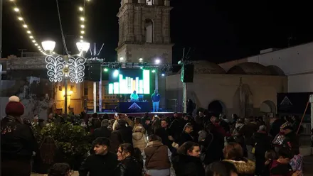 Plaza de la Merced en Rota con un escenario y un DJ, hay mucho público.