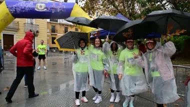 La lluvia ha provocado la suspensión de la San Silvestre Gaditana. un grupo de atletas con los chubasqueros y los paraguas en la línea de meta tras la decisión