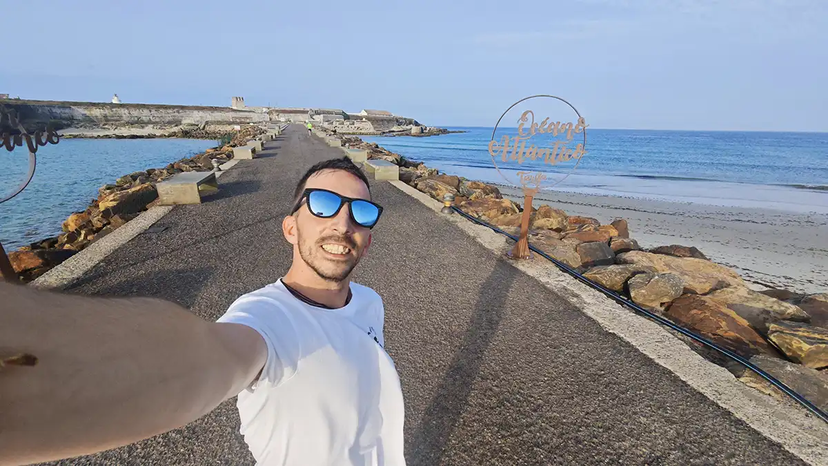 Carlos Romero sostiene el casco y sonríe frente al mar en Tarifa, con el Atlántico a un lado y el Mediterráneo al otro, punto de partida de su viaje en moto hacia el norte de Europa.