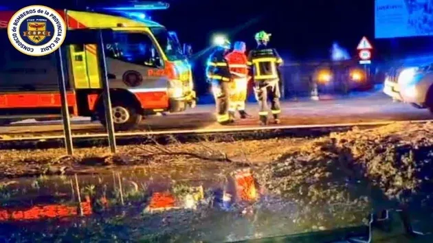 Bomberos junto a un camión y viendo la maniobra para sacar el coche del agua.