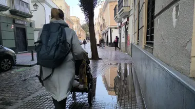 Una mujer pasa con su carrito de bebé junto a un charco en una acera en Cádiz. Foto: José Luis Porquicho Prada.