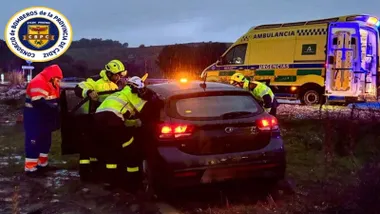 Bomberos sacando a la conductora del coche, de color negro, accidentado.