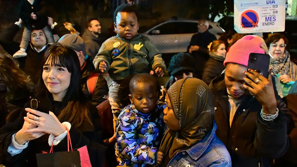 Público diverso formado por familias, niños y adultos de distintos orígenes culturales siguiendo la Cabalgata de Reyes Magos en una calle de Cádiz.
