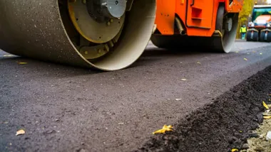 Apisonadora en color naranja compactando el asfalto.