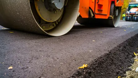 Apisonadora en color naranja compactando el asfalto.