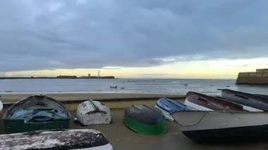 Playa de la Caleta llegando un claro tras el Castillo de San Sebastián y con barquitas en primer término. Foto: José Luis Porquicho Prada.