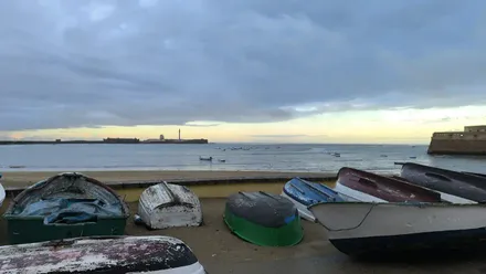 Playa de la Caleta llegando un claro tras el Castillo de San Sebastián y con barquitas en primer término. Foto: José Luis Porquicho Prada.
