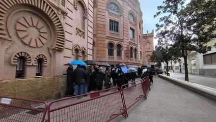 Cola en el Falla entradas COAC cantera con el público con paraguas por la lluvia