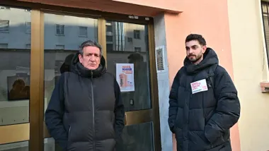 Dos personas, dos hombres, ante la puerta de la vivienda.