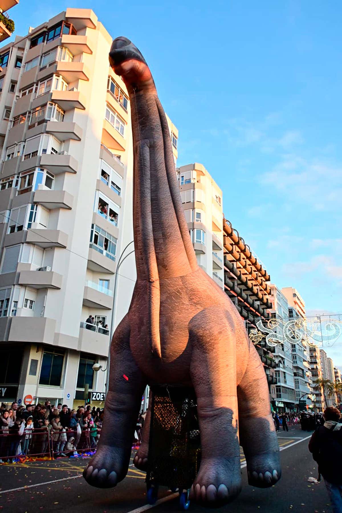 Figura animada de un dinosaurio T-Rex caminando por la calle durante la Cabalgata de Reyes Magos de Cádiz,.