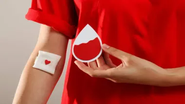 Persona con una gasa en el brazo tras donar sangre y una mancha en forma de corazón.