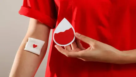 Persona con una gasa en el brazo tras donar sangre y una mancha en forma de corazón.