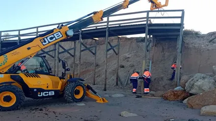 Trabajadores junto a una grúa apuntalando un paso dañado por el temporal.