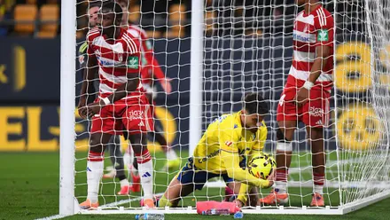 Álvaro García Pascual, delantero del Cádiz CF, aparece dentro de la portería recogiendo el balón tras marcar el gol del empate. A su lado se ve a un jugador del Granada CF, con el estadio del Nuevo Mirandilla de fondo.