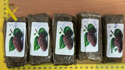 Cinco tabletas de hachís sobre una mesa de madera.