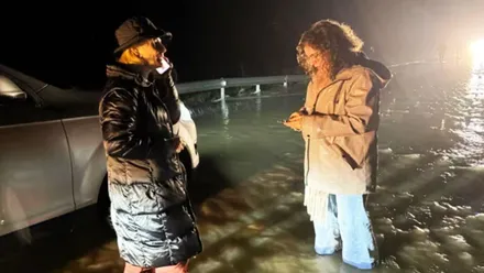 Dos personas con botas de agua en medio de una inundación.