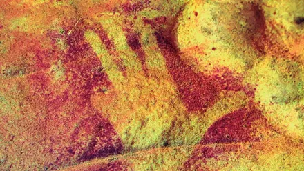 Mano negativa en una pared de una cueva en la zona de Gibraltar, destaca el color ocre.