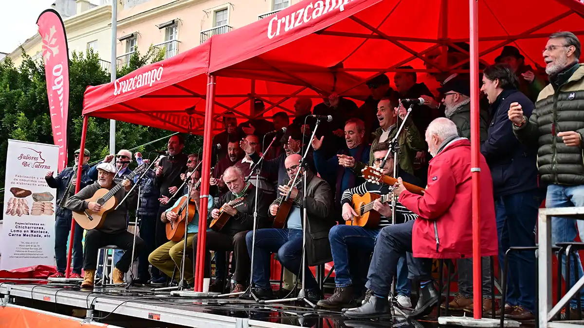 El coro callejero de Lusi Frade canta sobre las tarimas instaladas para las actuaciones y bajo la carpa para proteger a los grupos de la lluvia. Foto: Eulogio García.