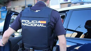 Policía Nacional de espalda abriendo la puerta de su vehículo policial.