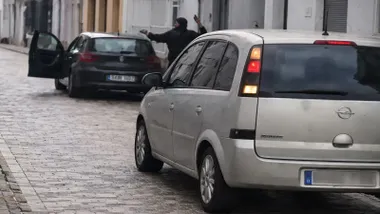 Dos coches aparcados y un hombre atacando a otro levantando la mano.