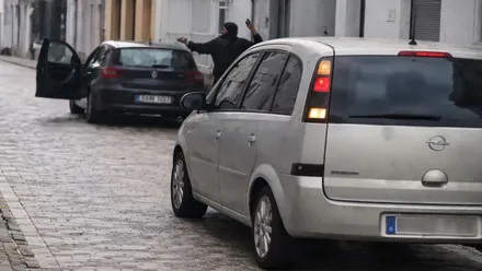 Dos coches aparcados y un hombre atacando a otro levantando la mano.