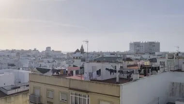Vista de varias azoteas del casco histórico de Cádiz con ropa tendida al aire libre. El cielo aparece despejado, aunque se aprecia una ligera bruma que indica humedad en el ambiente. Las fachadas y los tendederos reflejan una escena cotidiana de calma tras varios días de lluvia y viento.