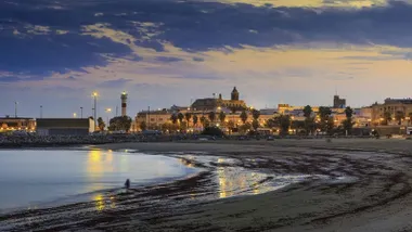 Ciudad costera de Rota al atardecer, destacan las luces encendidas del municipio.