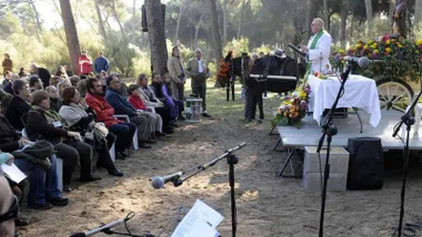 Misa oficiada por un sacerdote junto a un carro con un burro y público asistente.