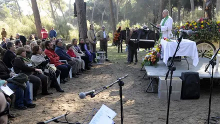 Misa oficiada por un sacerdote junto a un carro con un burro y público asistente.