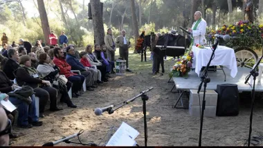 Misa oficiada por un sacerdote junto a un carro con un burro y público asistente.