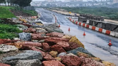 Piedras de gran tamaño invadiendo la carretera y conos marcando el mismo.