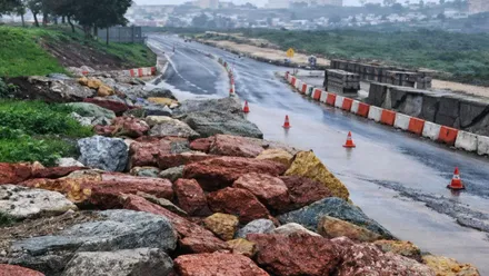 Piedras de gran tamaño invadiendo la carretera y conos marcando el mismo.