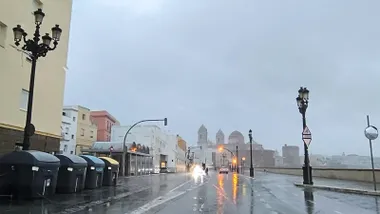 Lluvia en el parabrisas de un coche que circula por el Campo del Sur. Un autobús y otros autobuses circulan por una vía mojada. Cielo gris y la Catedral al fondo