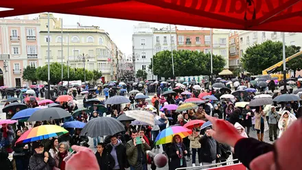Paraguas y chubasqueros para protegerse del agua mientras se escuchaban las primeras coplas dle Carnaval 2026 en la calle. Foto: Eulogio García.