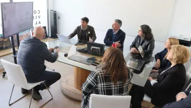 El alcalde mirando una pantalla junto a más personas en una habitación blanca.