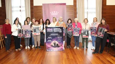 Grupo de mujeres en Chiclana con el cartel de los actos del (M en la ciudad.