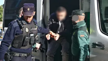 Bajando de un furgón el acusado del asesinato de Eva Aza, un policía nacional y un guardia civil lo tutelan.