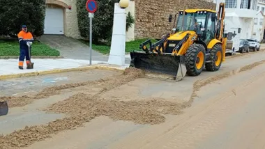 Excavadora amarilla bajando la pala para tomar arena.