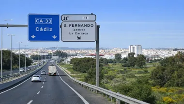 Parte de la CA-33 con carteles indicadores y vehículos circulando.