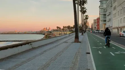 Una mujer circula en su bici por el Carril bici del Paseo MArítimo de Cádiz bajo un cielo despejado
