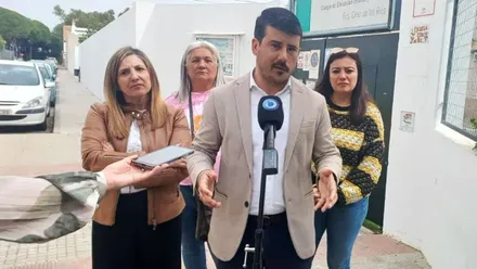 Varias personas, una delante de un micro hablando del estado de los colegios.