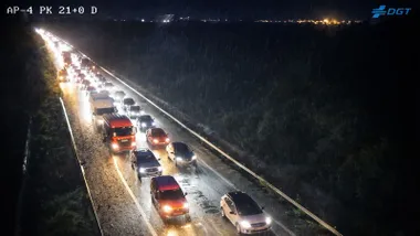 Vehículos parados en la AP-4, es de noche y tienen los faros encendidos.